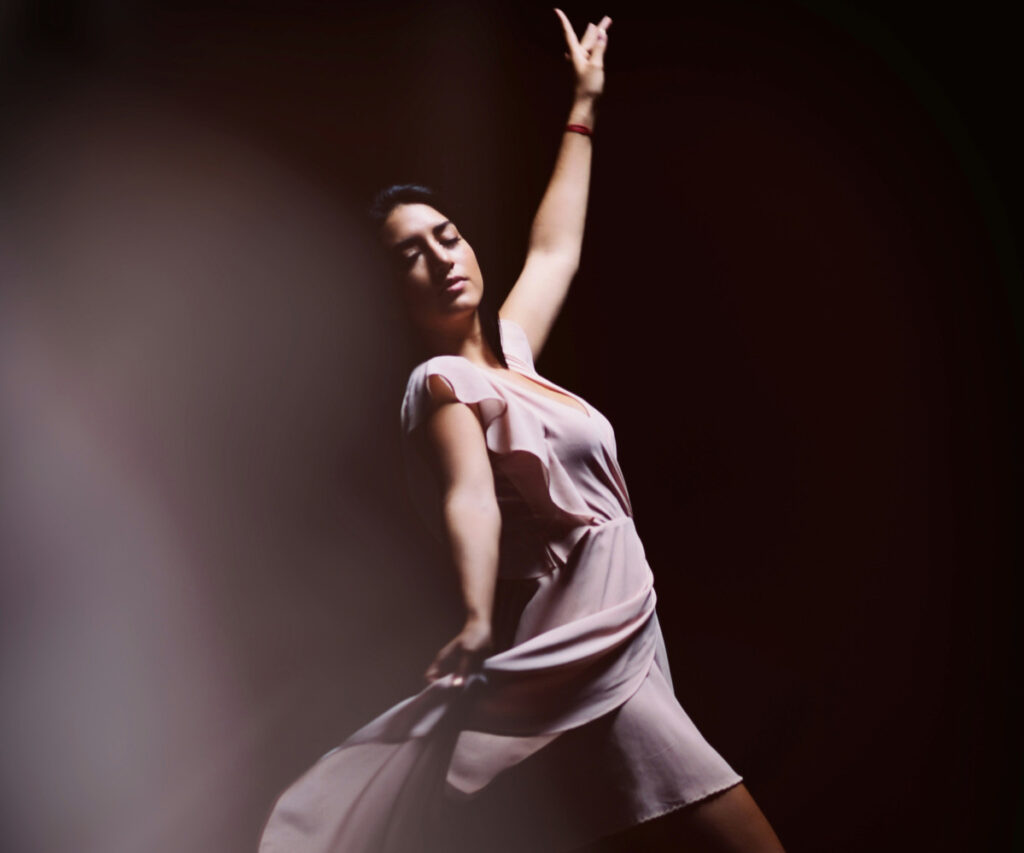 Dancer in a flowing dress performing a dramatic pose on stage