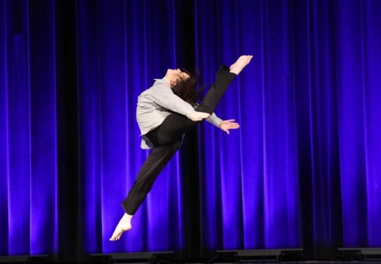 Dancer leaping on stage under blue lighting